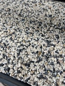 Close-up view of a textured surface covered with small, irregularly shaped gray and beige gravel stones, commonly used in Resin Rock applications.