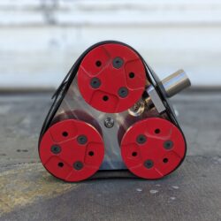 The NewGrind RX7 Mini - 3 Head Grinder accessory features a triangular frame with four red circular pads secured by black screws, shown resting on concrete with a blurred background.