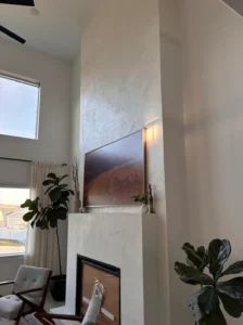 A modern living room with a tall white fireplace, a landscape photo above it, large windows, two armchairs, indoor plants, and sleek microtopping walls that add contemporary flair. A modern living room with a tall white fireplace, a landscape photo above it, large windows, two armchairs, indoor plants, and sleek microtopping walls that add contemporary flair.